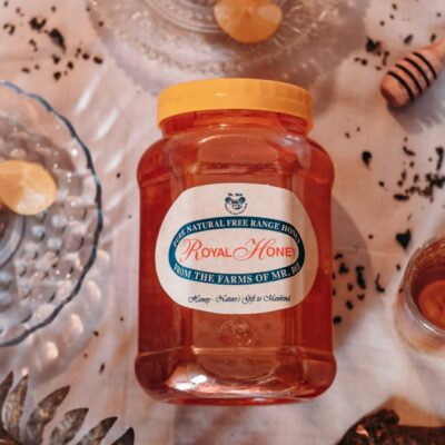 Jar of natural free range honey on a decorated table with glassware and ingredients.