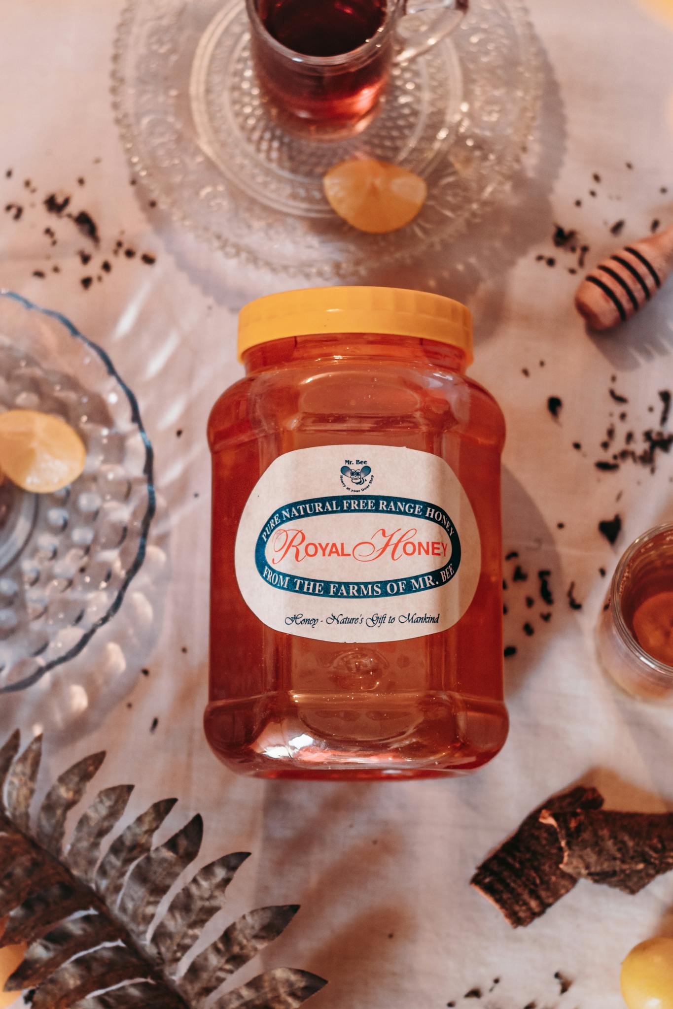 Jar of natural free range honey on a decorated table with glassware and ingredients.
